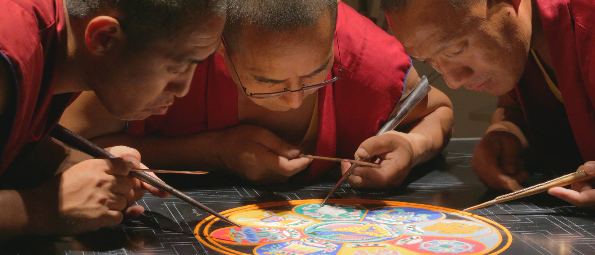 Tibetan monks creating sand paint mandala