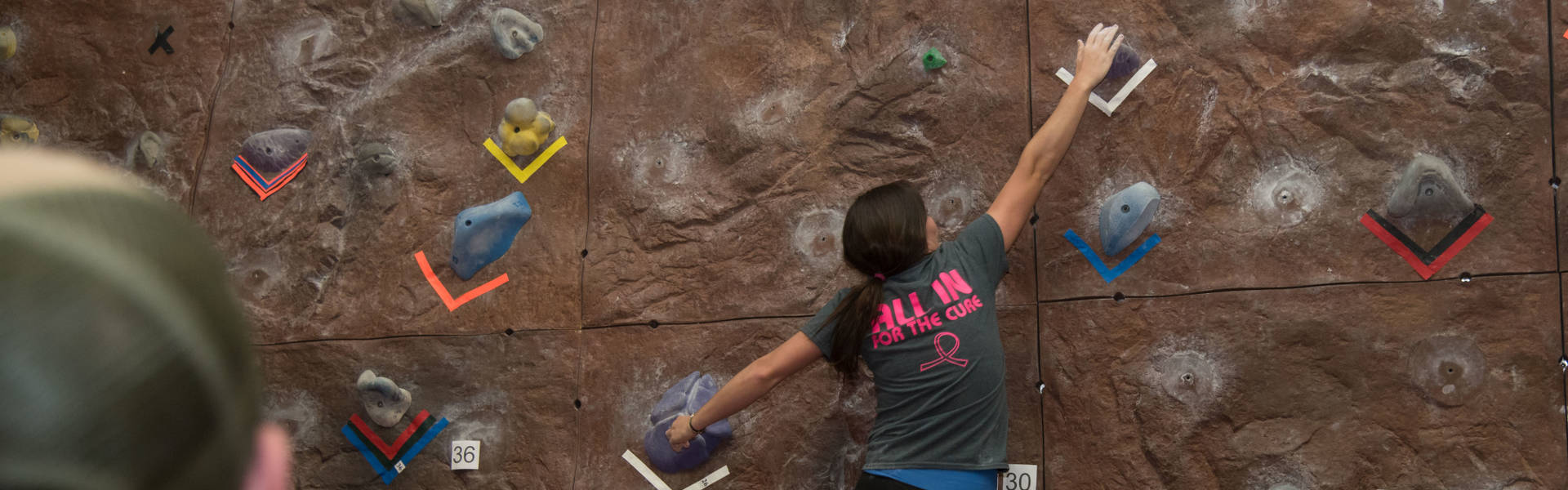 Female student climbing rock wall