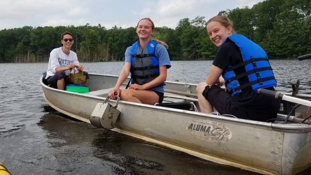 Biology students in canoe collecting moss samples.