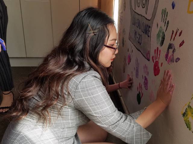 Blugold Diane Hang leaves her handprint on the artwork that the group created at Fresno Interdenominational Refugee Ministries.