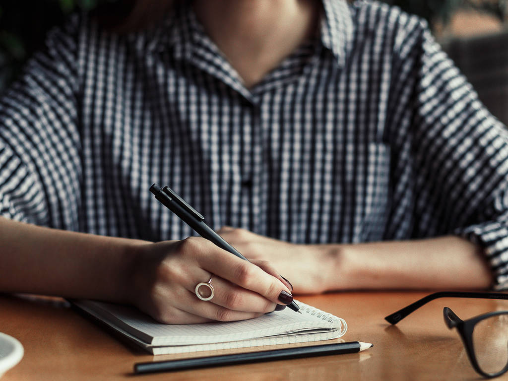 image of a person writing in a notebook