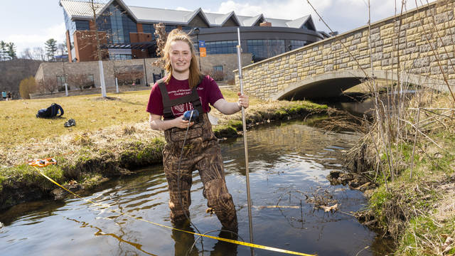 Senior Katherine Langfield collects research samples in Little Niagara Creek on lower campus. Langfield, who will graduate in May with a degree in geology, says research has been a big part of her undergraduate education at UW-Eau Claire.