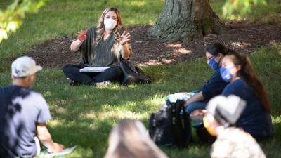 Outdoor class session, students sitting on grass