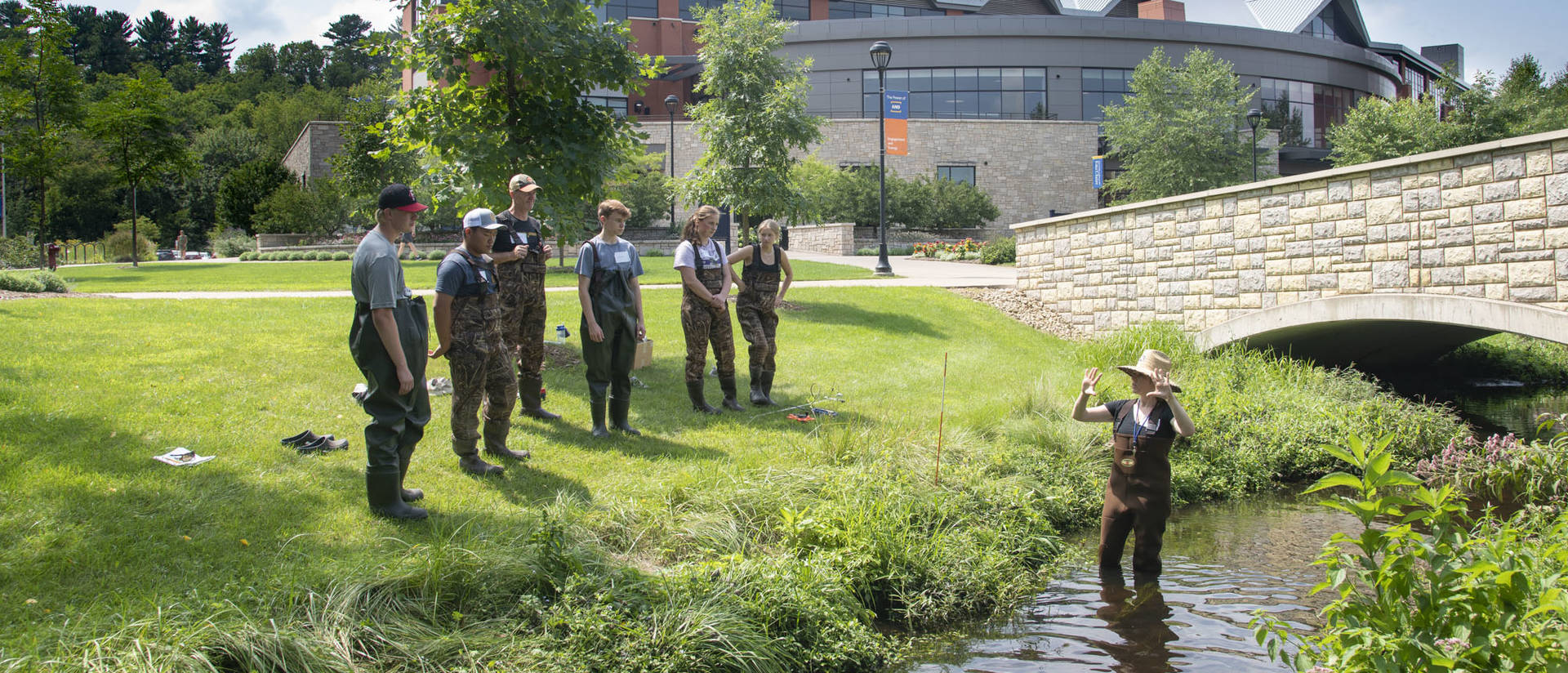 Hydrogeologist Dr. Sarah Vitale, an assistant professor of geology at UW-Eau Claire, explains stream flow measurement in Little Niagara Creek on campus to high school students who were part of a summer class on freshwater science. (Photo by Bill Hoepner)