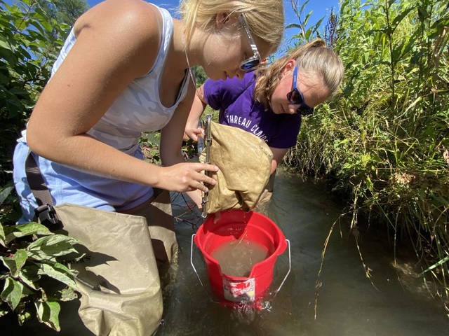 High school students Maddy Knauff, left, and Emma Johnson examine biodiversity in Gilbert Creek, west of Menomonie, as part of a class focused on helping young people understand Wisconsin waterways. (Submitted photo)
