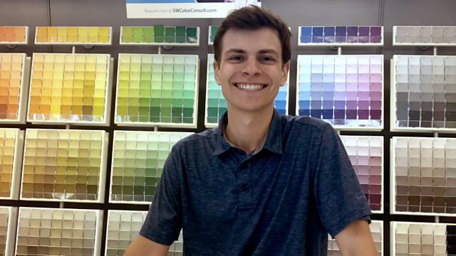 male student standing at counter in paint store