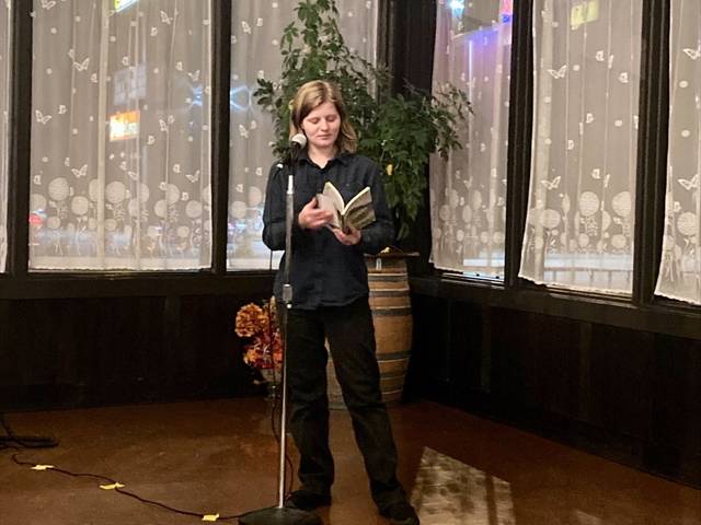A person reading from a book into a microphone