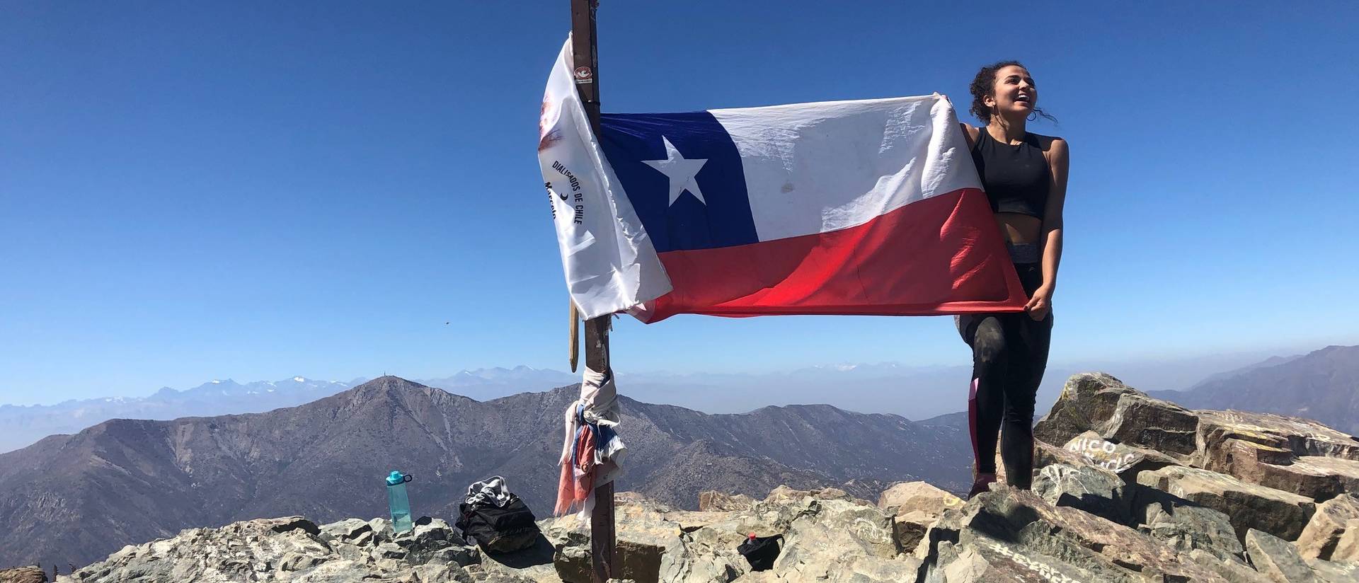 Student on mountain in Chile with flag of Chile