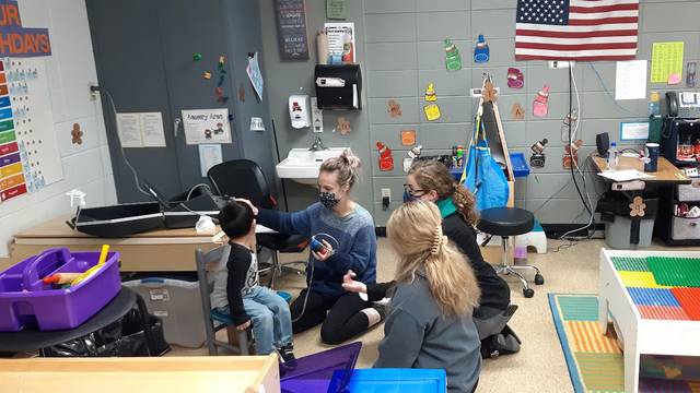 Carissa Phelps, CSD second year graduate student, Hope Wachholz, an undergraduate Spanish interpreter, and Arcadia Childcare Center Director Jolynn Bourland, work together to complete a young boy’s hearing screening. (Submitted photo)