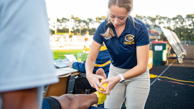 Student taping an ankle during a UWEC soccer game