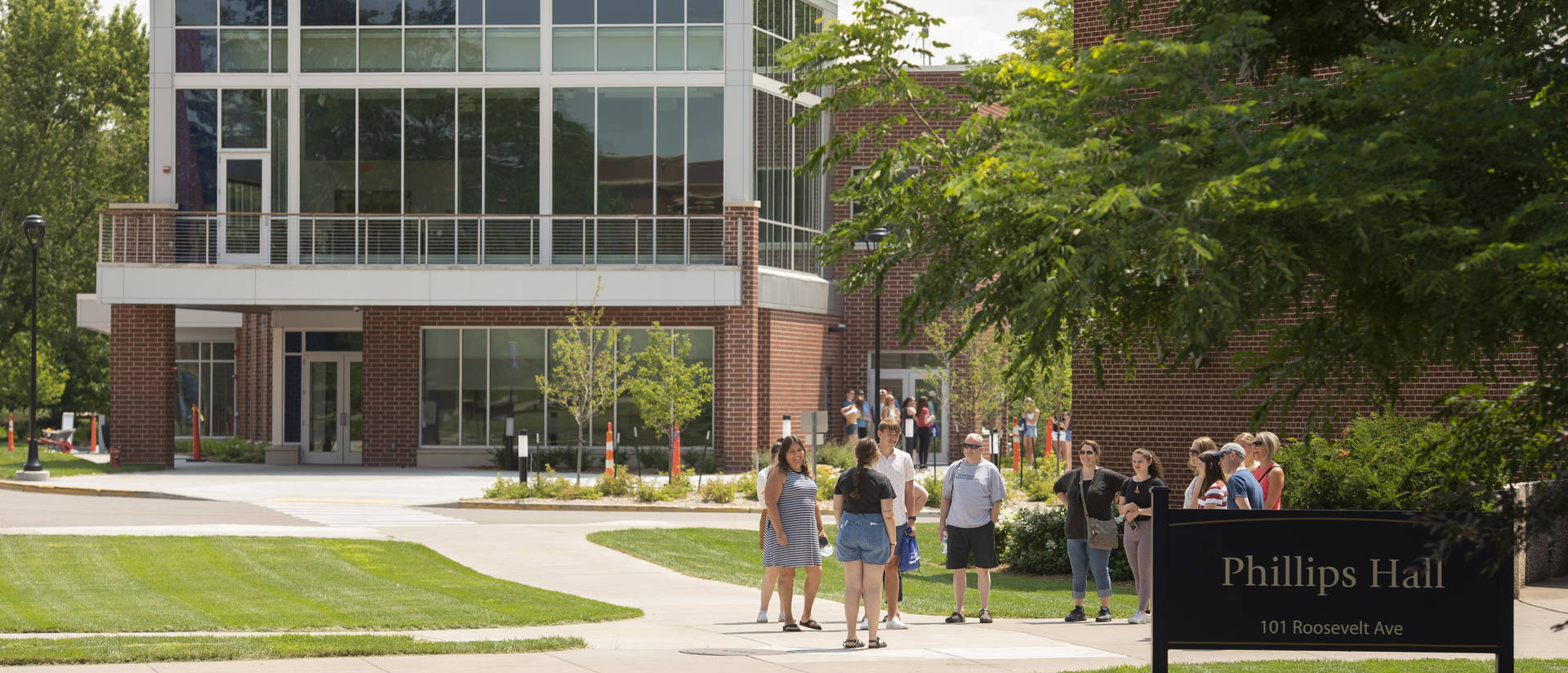 An Admissions tour walks past the Flesch Family Welcome Center on a summery day