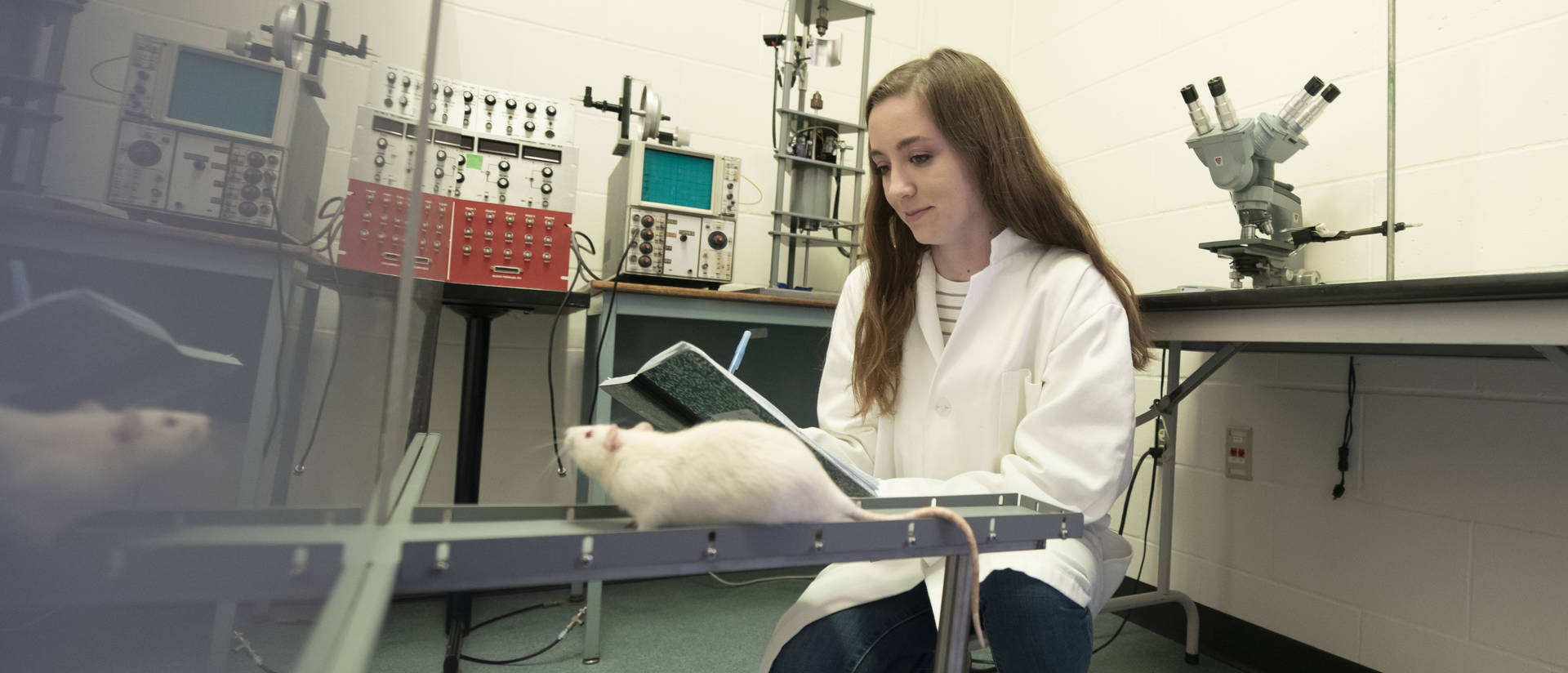 female student in neuroscience lab with white rat