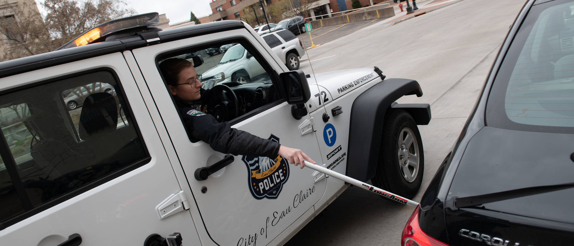 Person marks car tires in an Eau Claire Police parking enforcement vehicle.