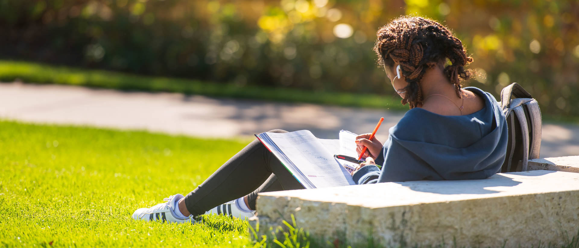 Student studies outside on the campus lawn.