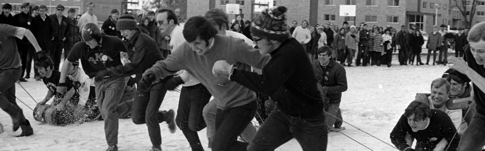 Male students competing in a sled race, ca. 1964-1971