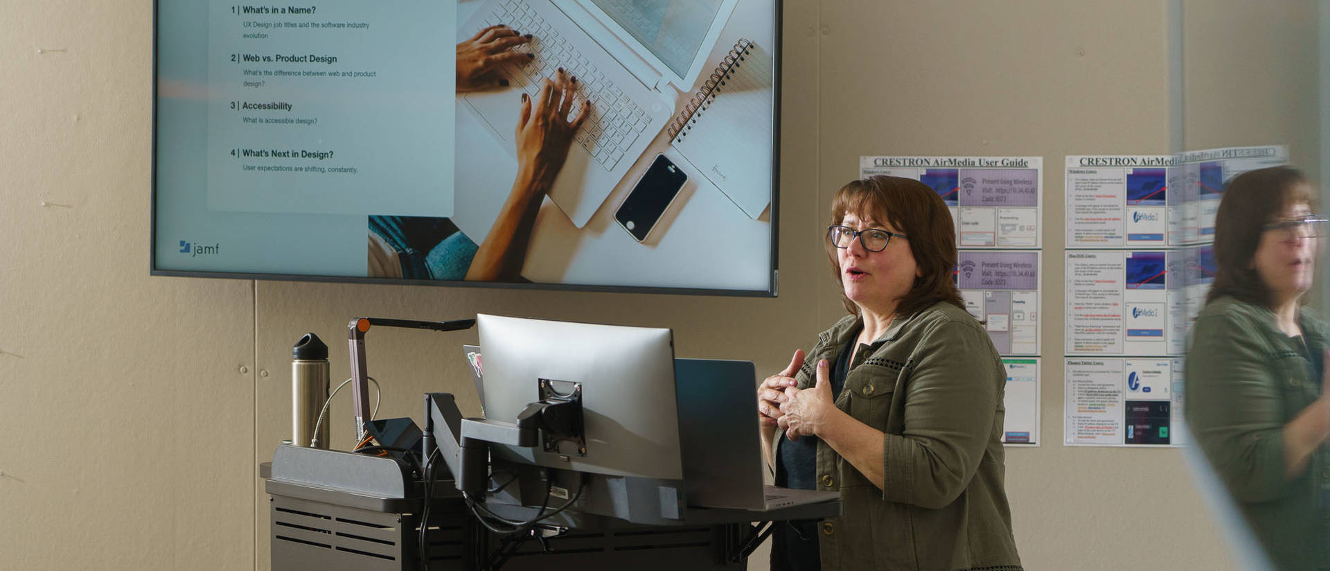 Woman in a classroom showing a Powerpoint on a screen.