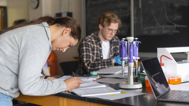Biochemistry students conduct an experiment in a science lab on campus.