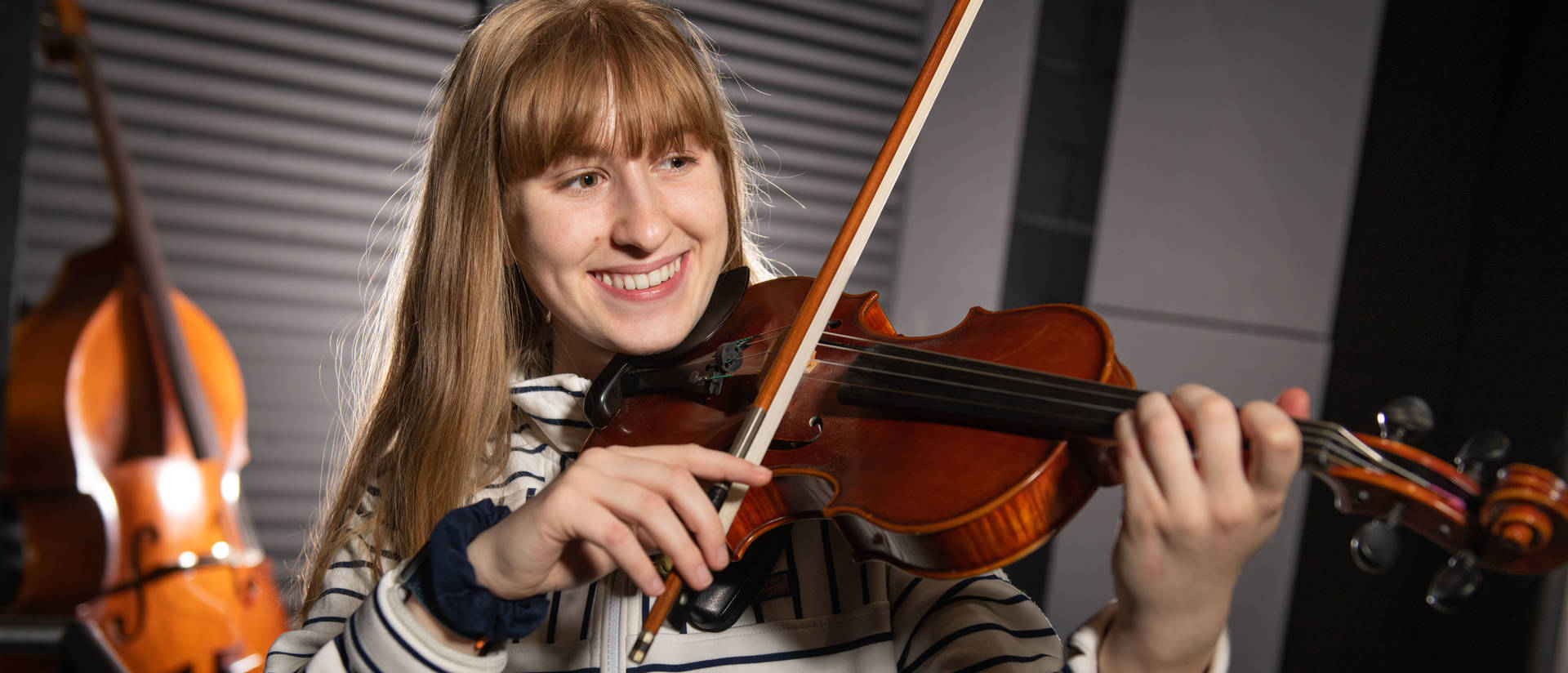 A person plays the violin while smiling.