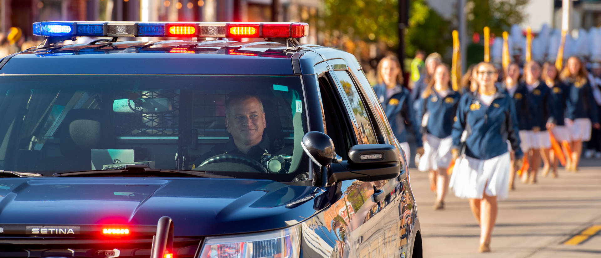 A UWEC police officer drives a police car at the front of the homecoming parade.