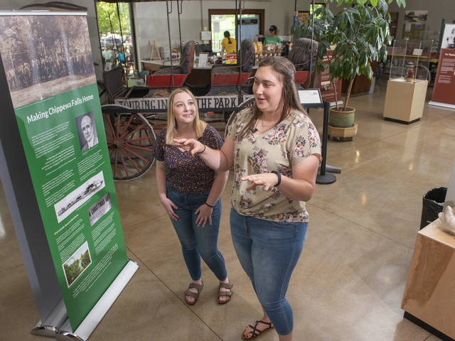 UW-Eau Claire public history graduate students Jordan Stish (left) and Alexi Linder discuss the exhibit they helped create in the Irvine Park Welcome Center in Chippewa Falls. (Photo by Shane Opatz)