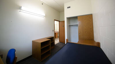 Single bedroom in Chancellors Hall apartment with closet, door opening to bathroom area.