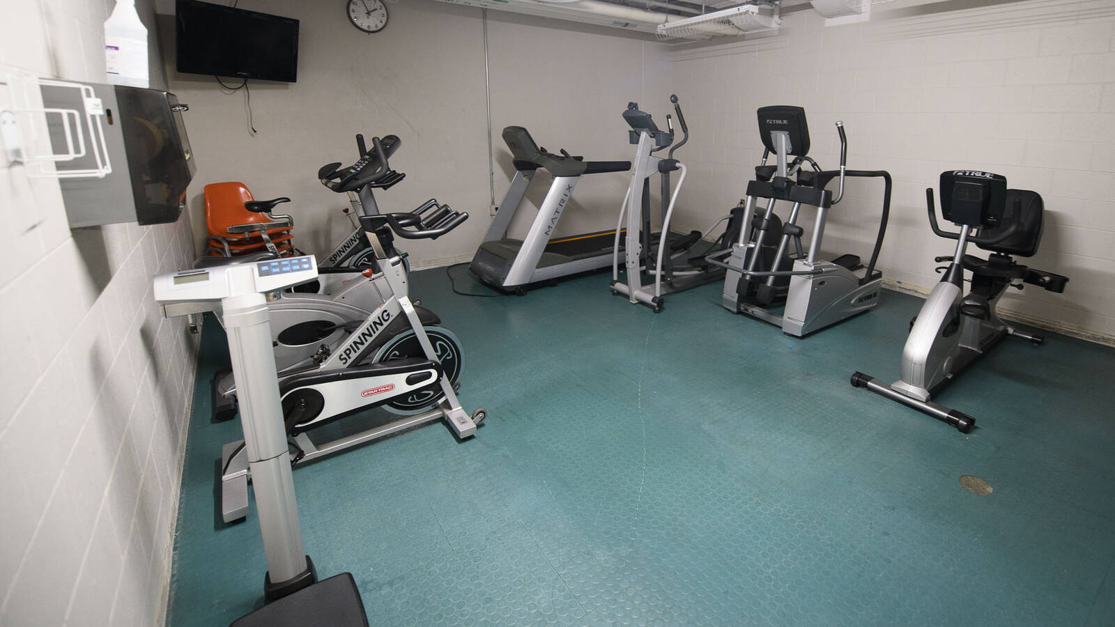 A room with exercise equipment including a treadmill, stationary bikes, and ellipticals.