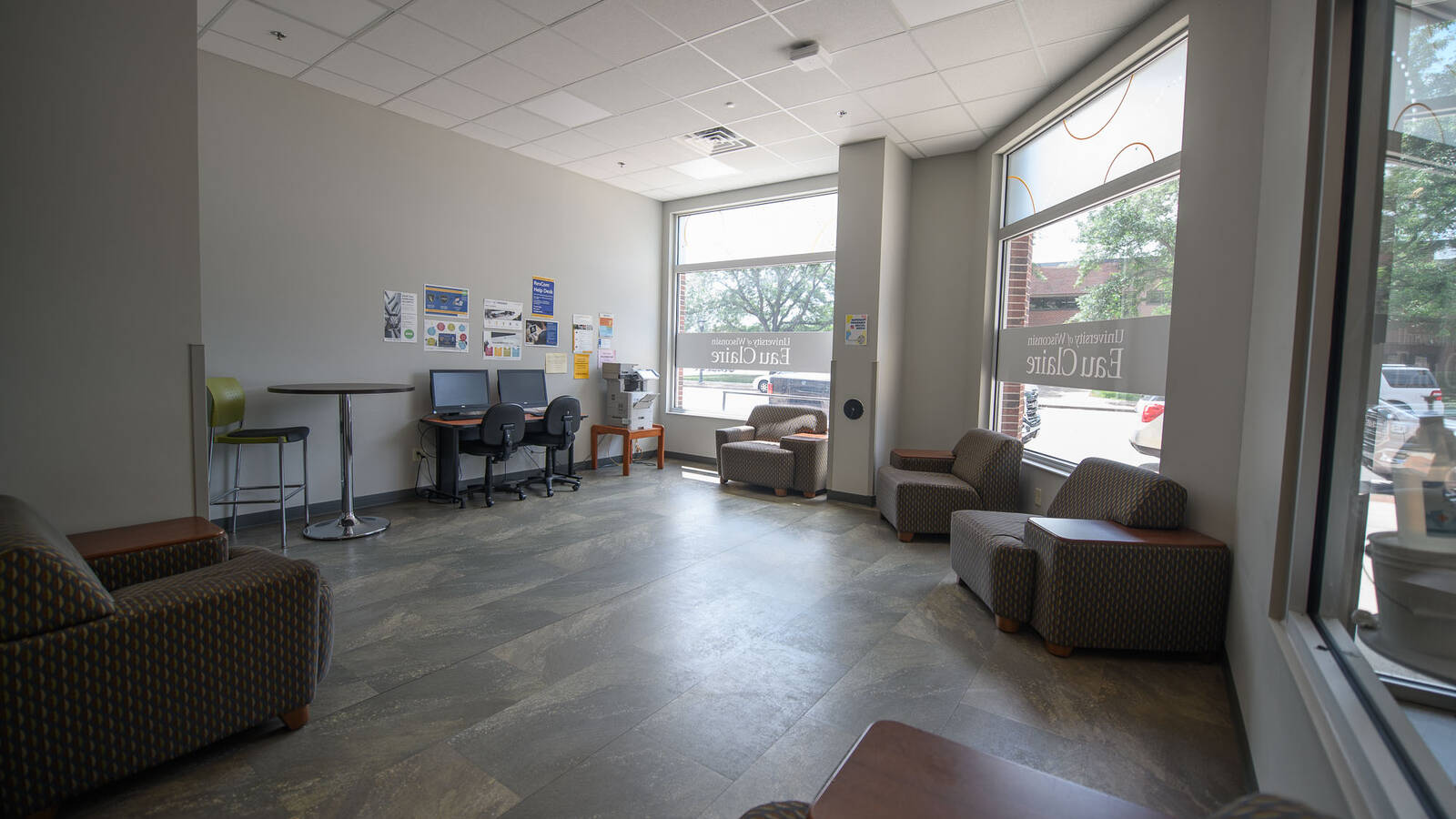 Lobby area of residence hall featuring two computers, an open space with armchairs and large windows