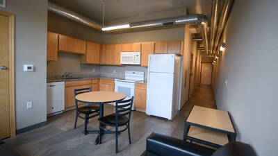 Residence hall kitchen equipped with oven, refrigerator, dishwasher and dining table with two chairs