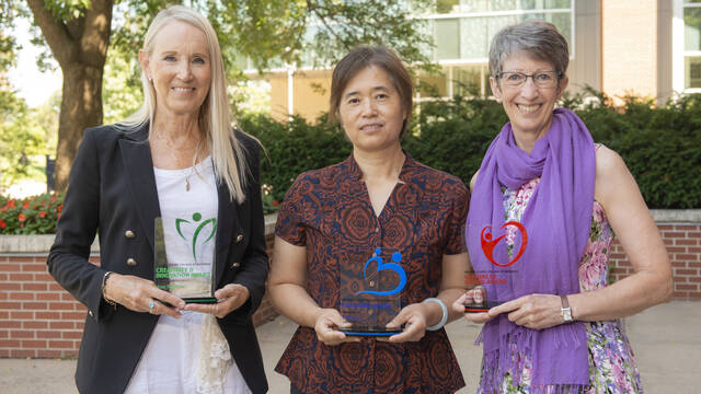 Ann Rupnow, Ling Liu, and Jean Pratt smile while holding awards received from the College of Business