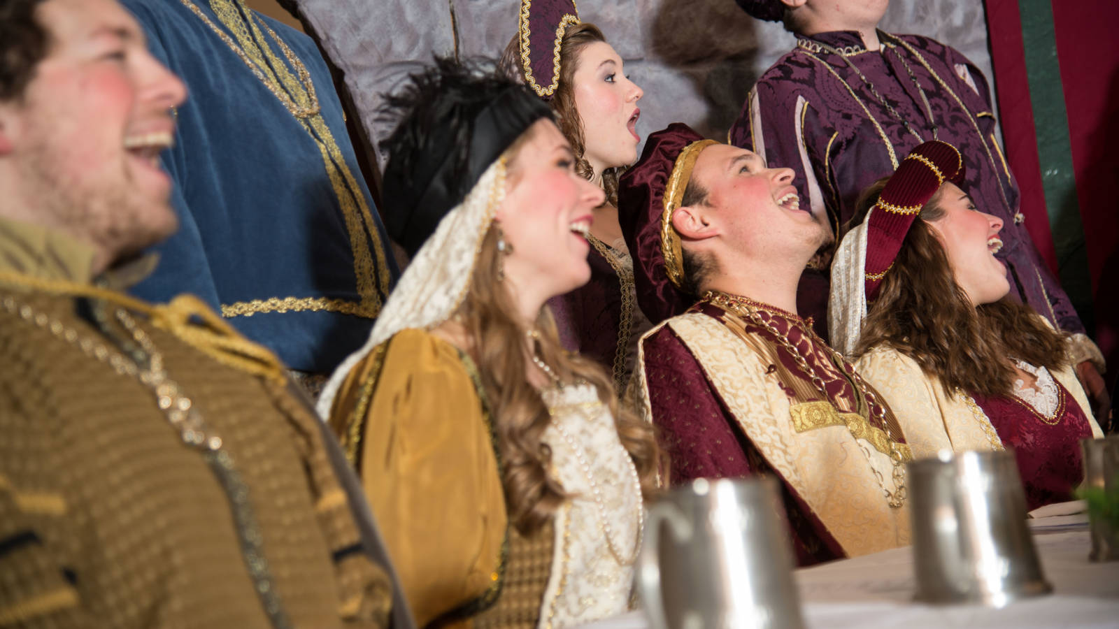 Members of the Ye Olde Madrigal Dinner laughing around the dinner table.