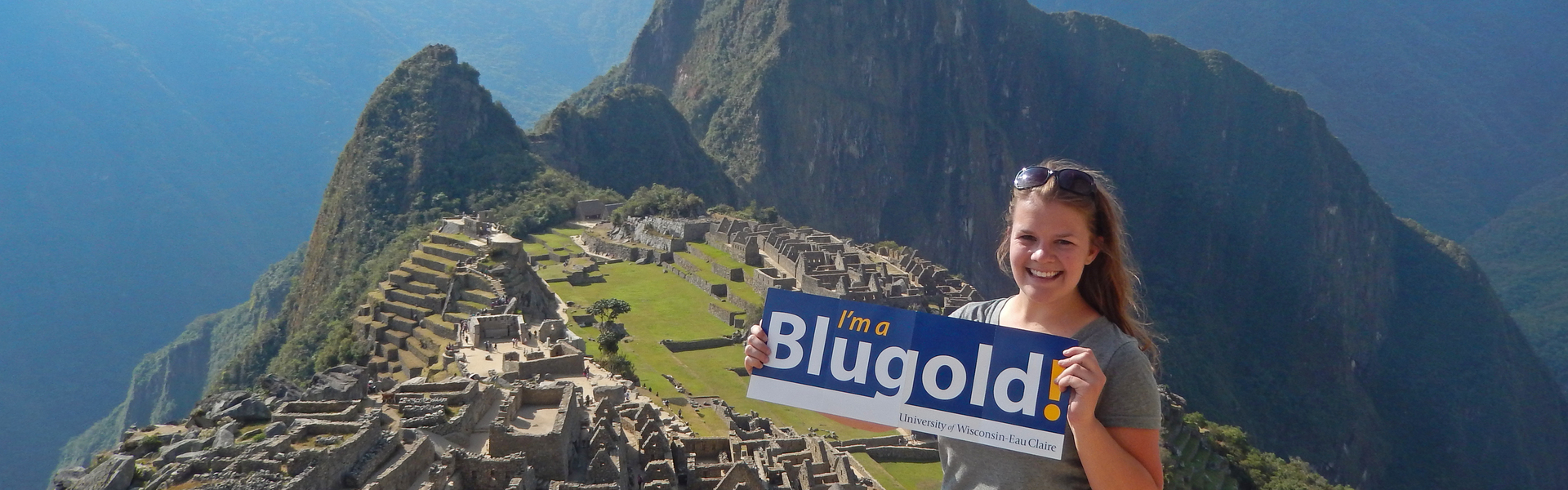 Student atop Machu Pichu in Peru holding I’m a Blugold sign.