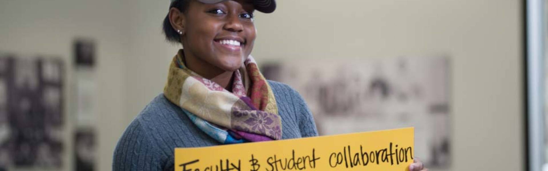 UW-Eau Claire student holds sign that reads “Faculty and student collaboration - you made it possible."
